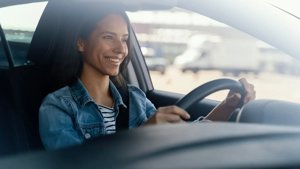 proteção veicular Mulher sorridente dirigindo um carro