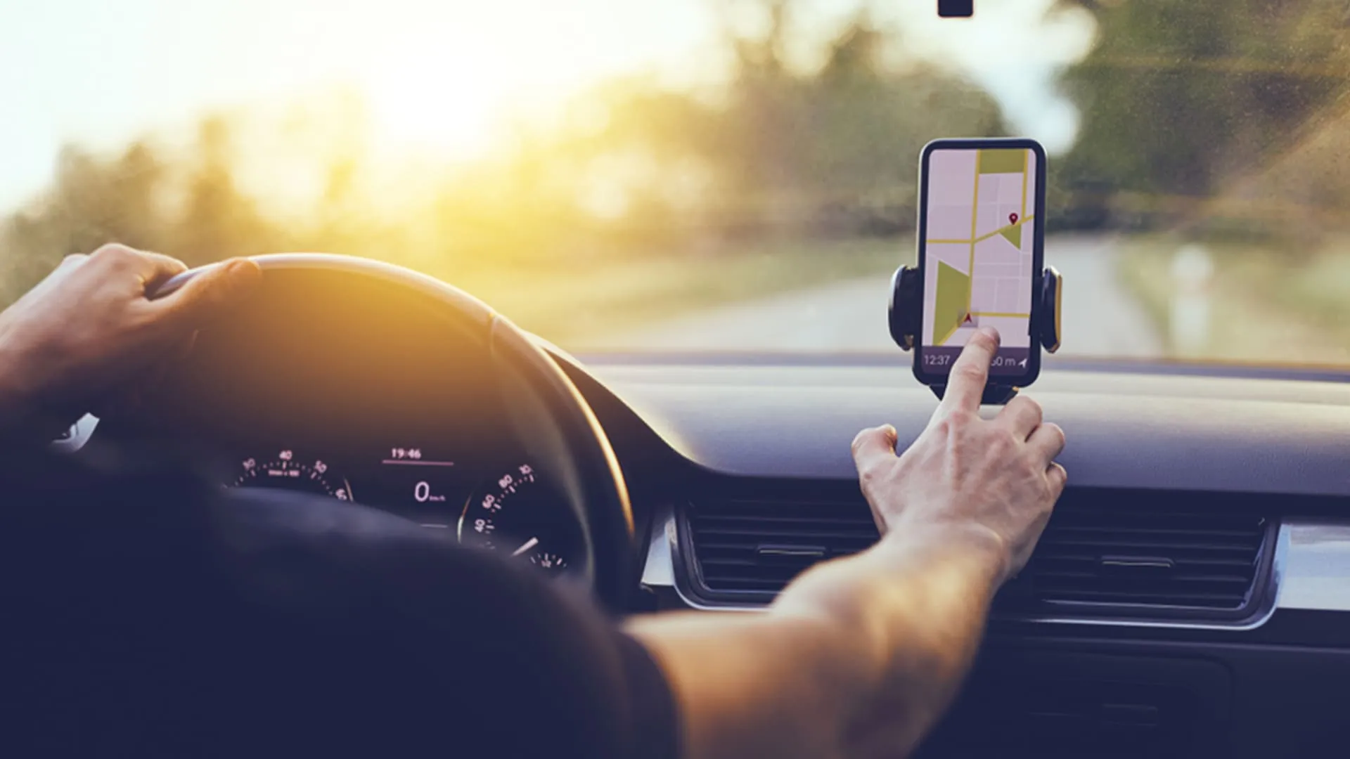 motorista de aplicativo homem clicando no GPS do seu celular, dentro do carro