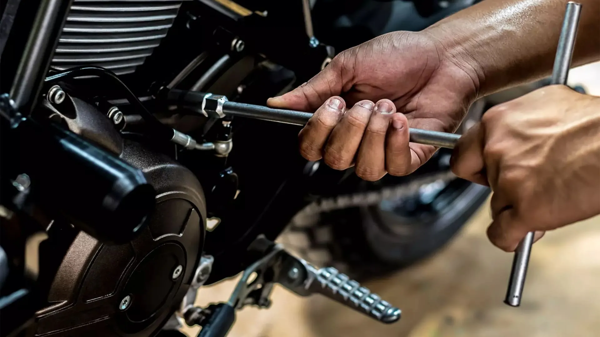 Manutenção mão com ferramenta encostando em moto