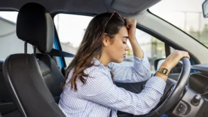 problemas mulher dentro do carro com olhos fechados e mão na cabeça