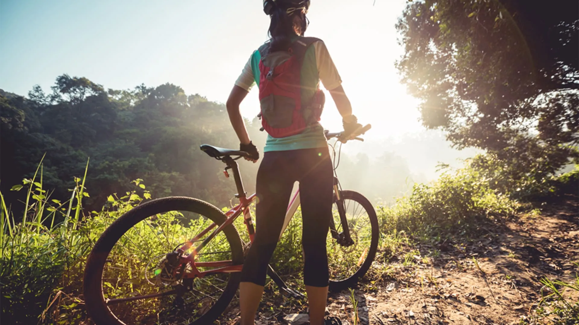 trilha de bike mulher segurando sua bicicleta durante trilha