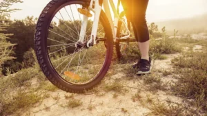 trilha de bike roda de bicileta com pe de pessoa sustentando bicicleta
