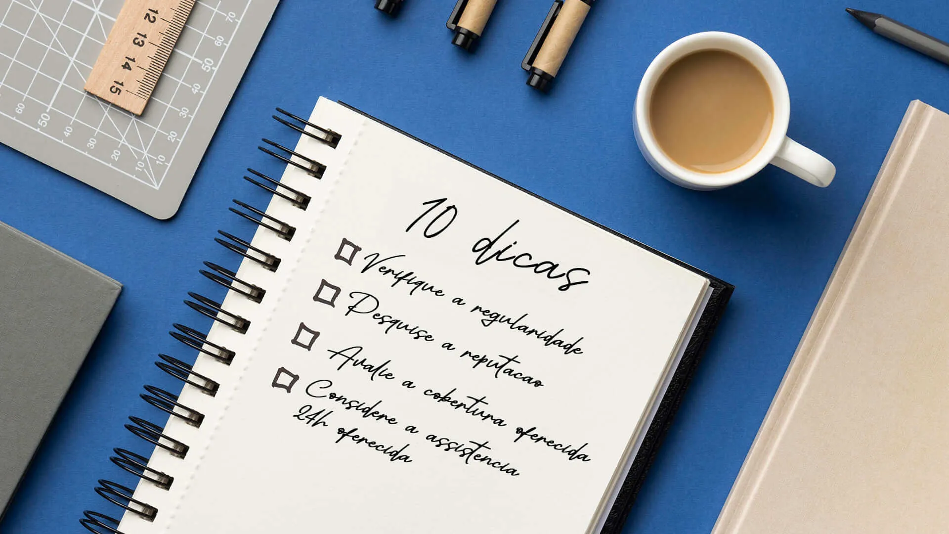 associação de proteção veicular mesa com caderno, xícará, canetas e regua. Dentro do caderno está escrito: 10 dias, verifique a regularidade, pesquise a reputação, Avalie a cobertura oferecida e Considere a assitencia 24h oferecida.