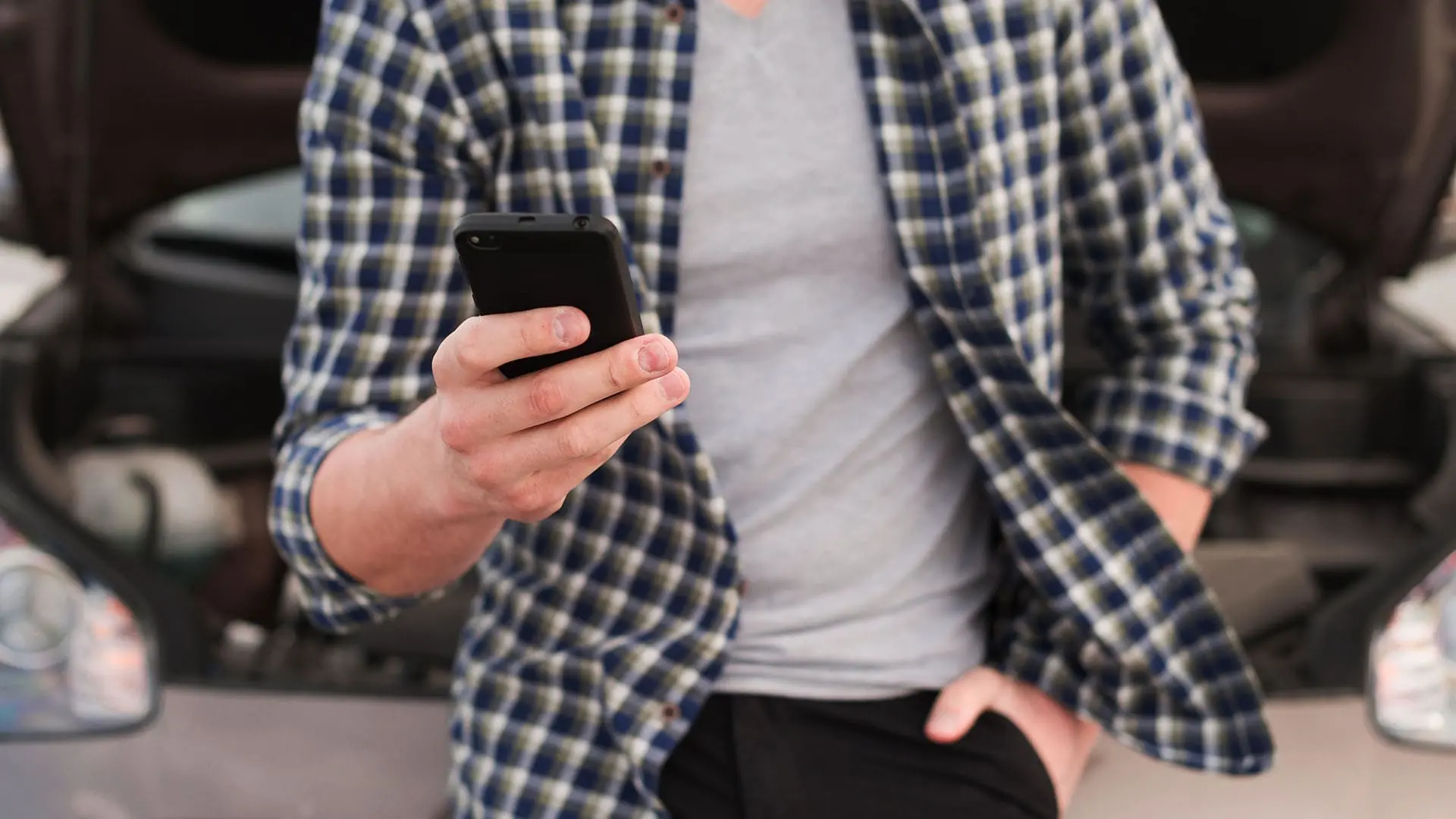 proteção veicular, homem com celular na mão na frente de carro