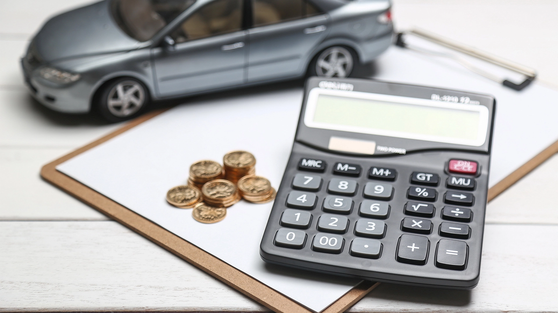 proteção veicular modelo-de-carro-calculadora-e-moedas-na-mesa-branca.